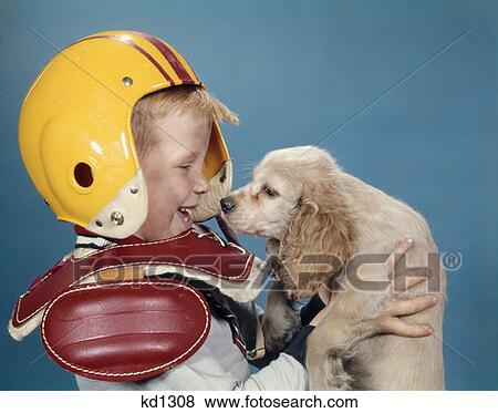 Laughing Little Boy In Football Uniform Looking At Blond Cocker Spaniel Puppy He Is Holding Up Studio Profile View Large Photo Image Stock Photo - Laughing Little Boy In Football Uniform Looking At Blond Cocker Spaniel Puppy He Is Holding Up Studio Profile. Fotosearch