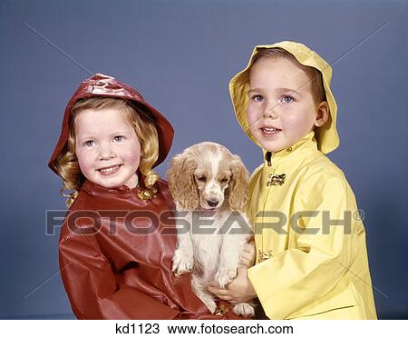 Little Boy And Girl In Raincoats And Hats Holding Cocker Spaniel Puppy Studio View Large Photo Image Stock Image - Little Boy And Girl In Raincoats And Hats Holding Cocker Spaniel Puppy Studio. Fotosearch