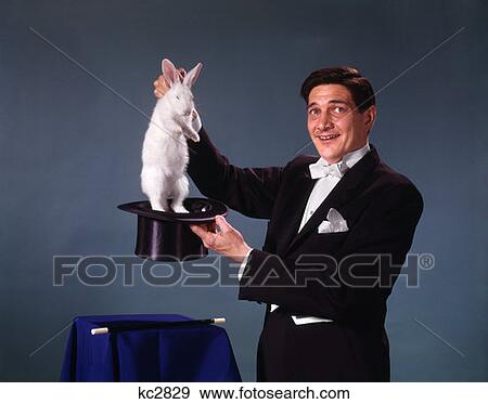 Magician Man Black Coat Blue Background Pulling Rabbit Out Of Top Hat Trick Magic Illusion Sleight Of Hand View Large Photo Image Stock Photo - Magician Man Black Coat Blue Background Pulling Rabbit Out Of Top Hat Trick Magic Illusion Sleight Of Hand. Fotosearch