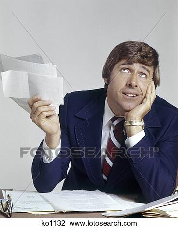 Stock Image - Man Office Business Paperwork Work Overwhelmed Overwhelming Defeat 1970 1970S Retro. Fotosearch