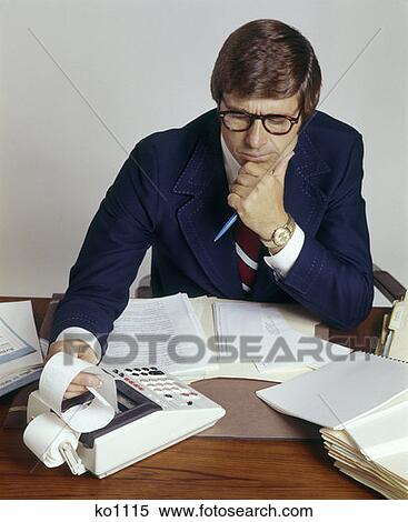 Stock Photography - Man Office Business Working Calculator Adding Machine Perplexed Accountant 1970 1970S Retro. Fotosearch