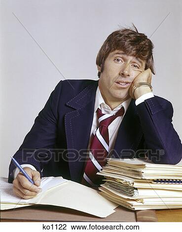 Stock Image - Man Office Business Working Frustrated Overwhelmed Overwhelming Workload 1970 1970S Retro. Fotosearch