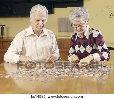Stock Photography - Retro Elderly Couple 1970 1970S Doing A Puzzle. Fotosearch