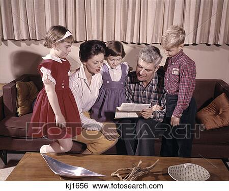 Stock Photograph - Retro Family Crowded Around Living Room Viewing Letter. Fotosearch