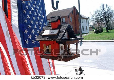Stock Image - Schoolhouse Style Birdhouse Hanging By U. S. Flag Patriotic . Fotosearch