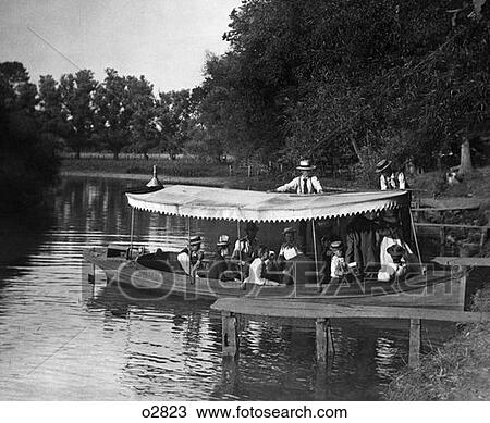 Stock Image - Turn Of The Century Group In Boat With Canopy Being Pushed Out Into Lake . Fotosearch