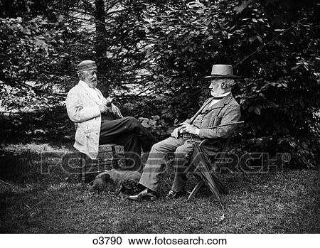 Turn Of The Century Pair Of Men Sitting Outside In Chairs Among Trees Smoking Cigars & Talking With Dog Lying At Their Feet View Large Photo Image Stock Image - Turn Of The Century Pair Of Men Sitting Outside In Chairs Among Trees Smoking Cigars & Talking With Dog Lying At Their Feet. Fotosearch