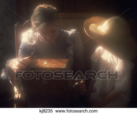 Stock Photography - Two Little Girls Wearing White Dress And Straw Hat In Attic Sunlight Looking At Antique Wood Box Soft Focus Nostalgia . Fotosearch