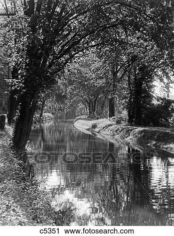 Stock Image - Water In Canal Reflecting Trees Lining Its Banks . Fotosearch