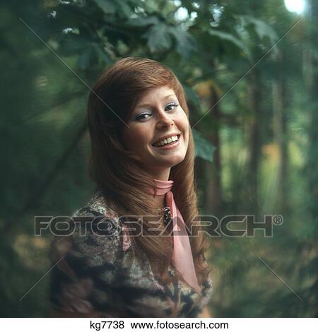 Stock Photo - Woman With Long Red Hair Standing Outside Near Trees 1970 1970S. Fotosearch