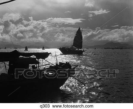 Stock Image - 1920 1920S 1930 1930S Sunset Hong Kong Harbor With Silhouetted Junk Junks Boat Boats Dramatic Rrr Retro China Chinese . Fotosearch