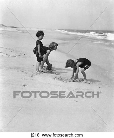 1920 1920S 3 Kids Boys Girls Boy Digging Sand Girl Emptying Sand Pail Bucket Play Playing Summer Fun New Jersey Shore Retro View Large Photo Image Stock Photo - 1920 1920S 3 Kids Boys Girls Boy Digging Sand Girl Emptying Sand Pail Bucket Play Playing Summer Fun New Jersey Shore Retro. Fotosearch