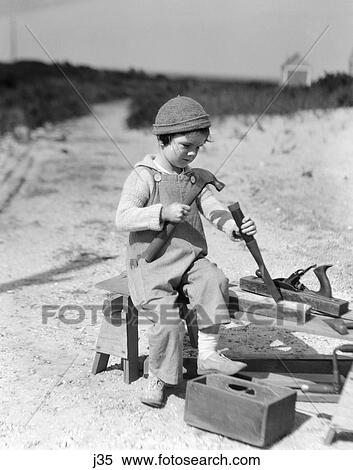 1920 1920S Boy Cap Overalls Using Hammer Chisel Working With Wood Carpenter Carpenters Tools Repair Repairing Build Retro View Large Photo Image Stock Photography - 1920 1920S Boy Cap Overalls Using Hammer Chisel Working With Wood Carpenter Carpenters Tools Repair Repairing Build Retro. Fotosearch