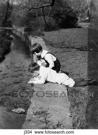 1920 1920S Two Boys Playing In Water Stream Creek Boy Lying Ground String Fishing Angling Summer Fun Play Retro View Large Photo Image Picture - 1920 1920S Two Boys Playing In Water Stream Creek Boy Lying Ground String Fishing Angling Summer Fun Play Retro . Fotosearch