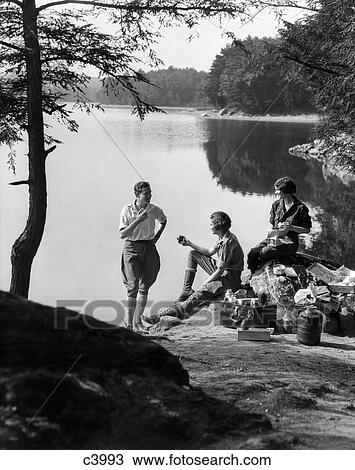 1920S 1930S 3 People Picnicking By Lake Man Wearing Jodhpurs Standing Two Seated Women Berkshires Ma Onata Lake View Large Photo Image Stock Image - 1920S 1930S 3 People Picnicking By Lake Man Wearing Jodhpurs Standing Two Seated Women Berkshires Ma Onata Lake. Fotosearch