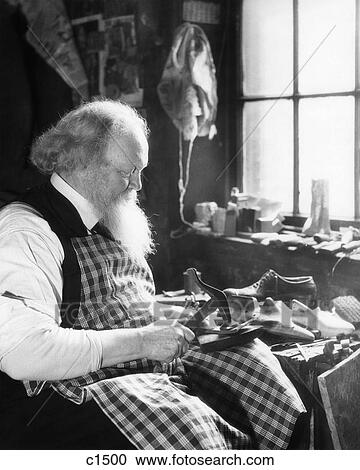 1920S 1930S Bearded Elderly Cobbler By Window At Workbench Repairing A Shoe Wearing A Checked Apron And Holding A Hammer View Large Photo Image Stock Image - 1920S 1930S Bearded Elderly Cobbler By Window At Workbench Repairing A Shoe Wearing A Checked Apron And Holding A Hammer . Fotosearch