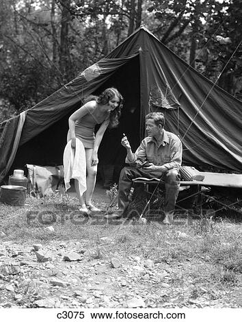 1920S 1930S Camping Couple Man Sitting By Tent With Fishing Rod Woman Standing Wearing Bathing Suit View Large Photo Image Stock Photography - 1920S 1930S Camping Couple Man Sitting By Tent With Fishing Rod Woman Standing Wearing Bathing Suit . Fotosearch