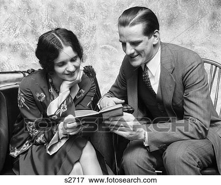 1920S 1930S Couple Reading Sharing Book Smiling Man Pointing Out Passage In Book To Woman Fashion Clothes View Large Photo Image Stock Photo - 1920S 1930S Couple Reading Sharing Book Smiling Man Pointing Out Passage In Book To Woman Fashion Clothes . Fotosearch