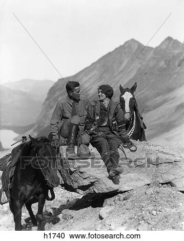 1920S 1930S Couple Sitting On Rocks Holding Reins Of Trail Horses In The Plain Of 6 Glaciers Lake Louise Canada View Large Photo Image Stock Image - 1920S 1930S Couple Sitting On Rocks Holding Reins Of Trail Horses In The Plain Of 6 Glaciers Lake Louise Canada. Fotosearch