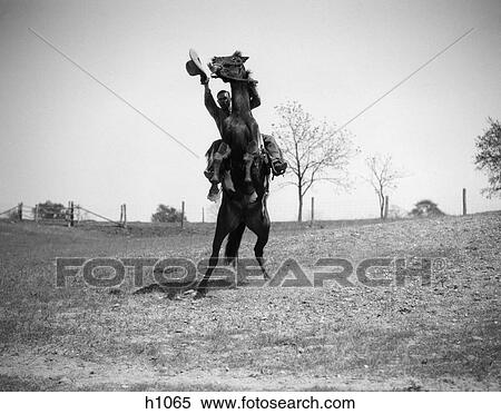 Stock Photography - 1920S 1930S Cowboy On Horse Rearing Up Man Waving Hat In Hand . Fotosearch