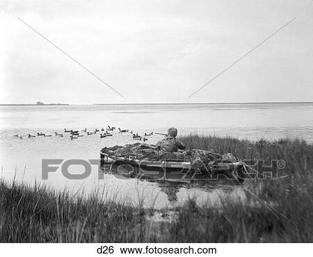 Stock Photograph - 1920S 1930S Man Camouflaged Boat Duck Shooting Barnegat Bay New Jersey . Fotosearch