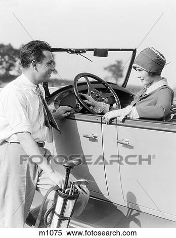 1920S 1930S Man In Shirt And Tie Holding Golf Bag Standing Next To Woman Sitting In A Convertible Sedan Hand On Steering Wheel View Large Photo Image Stock Photography - 1920S 1930S Man In Shirt And Tie Holding Golf Bag Standing Next To Woman Sitting In A Convertible Sedan Hand On Steering Wheel. Fotosearch