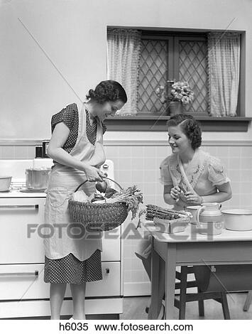 1920S 1930S Two Women At Kitchen Table With A Basket Of Vegetables Asparagus Stove View Large Photo Image Stock Photography - 1920S 1930S Two Women At Kitchen Table With A Basket Of Vegetables Asparagus Stove . Fotosearch