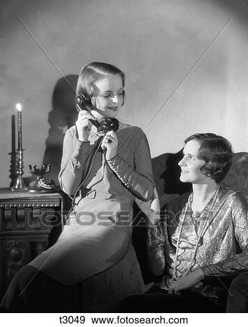 1920S 1930S Two Women One Talking On Phone Other Sitting In Chair Candle Light View Large Photo Image Stock Photo - 1920S 1930S Two Women One Talking On Phone Other Sitting In Chair Candle Light . Fotosearch