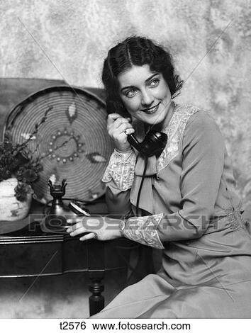 1920S 1930S Woman On Phone Sitting By & Leaning Over Table With Phone Decorative Plate Navaho Basket & Flowers Smiling View Large Photo Image Stock Photograph - 1920S 1930S Woman On Phone Sitting By & Leaning Over Table With Phone Decorative Plate Navaho Basket & Flowers Smiling . Fotosearch