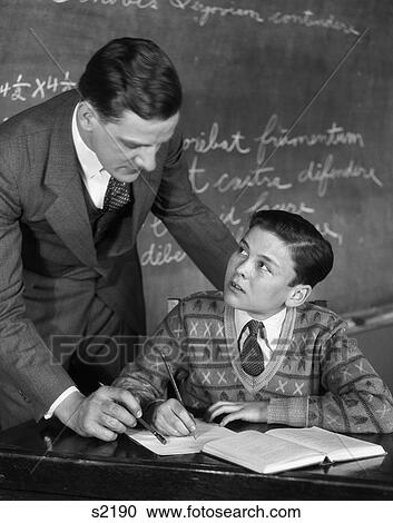 1920S Classroom Male Teacher Helping Boy At Desk - Blackboard In Background View Large Photo Image Stock Image - 1920S Classroom Male Teacher Helping Boy At Desk - Blackboard In Background . Fotosearch