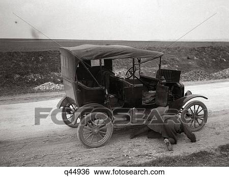 1920S Man On His Hands And Knees Looking Under Model T Broken Down On Roadside View Large Photo Image Stock Photograph - 1920S Man On His Hands And Knees Looking Under Model T Broken Down On Roadside . Fotosearch