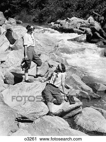1920S Pair Of Women On Rocks By Creek One Holding Camera View Large Photo Image Stock Image - 1920S Pair Of Women On Rocks By Creek One Holding Camera . Fotosearch