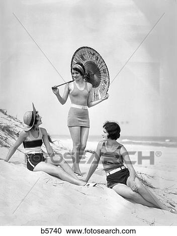 1920S Three Smiling Women In Swimsuits At The Beach 2 Are Sitting And One Is Standing Holding An Oriental Paper Umbrella View Large Photo Image Stock Image - 1920S Three Smiling Women In Swimsuits At The Beach 2 Are Sitting And One Is Standing Holding An Oriental Paper Umbrella . Fotosearch