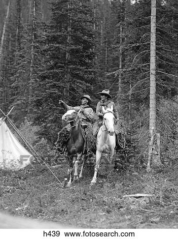 1920S Two Men Riding Horses Through Camp Grounds In Forest Cowboy Hat Tent Adventure Cowboys Both Are Wearing Angora Chaps View Large Photo Image Stock Photo - 1920S Two Men Riding Horses Through Camp Grounds In Forest Cowboy Hat Tent Adventure Cowboys Both Are Wearing Angora Chaps. Fotosearch