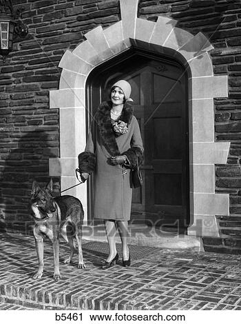 1920S Upscale Fashionable Woman Cloche Hat And Coat Fur Trim And German Shepherd Dog On Leash In Arched Doorway View Large Photo Image Stock Image - 1920S Upscale Fashionable Woman Cloche Hat And Coat Fur Trim And German Shepherd Dog On Leash In Arched Doorway . Fotosearch