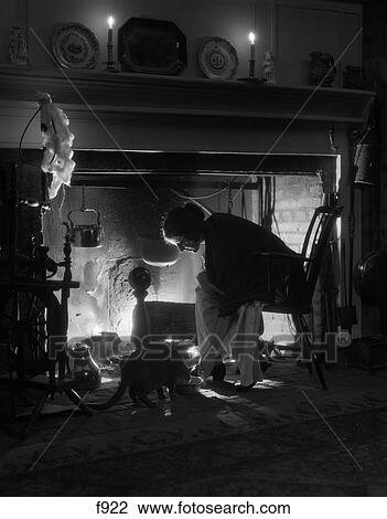 1920S Woman Sitting At Fireplace In Chair Leaning Over Put Bowl To Feed Cat On Floor Only Light From Fire & Candles View Large Photo Image Stock Image - 1920S Woman Sitting At Fireplace In Chair Leaning Over Put Bowl To Feed Cat On Floor Only Light From Fire & Candles. Fotosearch