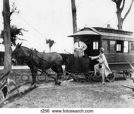 1920S Woman Stepping Up Onto Mule-Drawn Train Car With Conductor Driver Standing At Front View Large Photo Image Stock Photograph - 1920S Woman Stepping Up Onto Mule-Drawn Train Car With Conductor Driver Standing At Front . Fotosearch