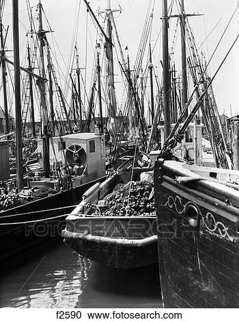 Stock Image - 1930 1930S 1920 1920S Commercial Fishing Shipping Ships Boat Boating Boats Sail Sailing Sails Fish Ocean Marina Retro . Fotosearch