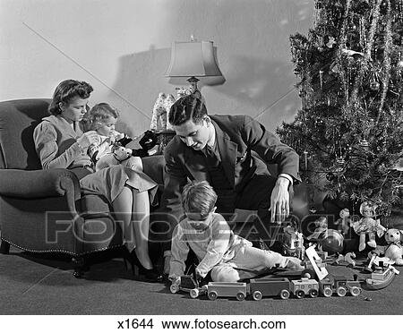 1930 1930S 1940 1940S Family Around Christmas Tree Boy Playing With Train Dad Helping Mom View Large Photo Image Picture - 1930 1930S 1940 1940S Family Around Christmas Tree Boy Playing With Train Dad Helping Mom. Fotosearch