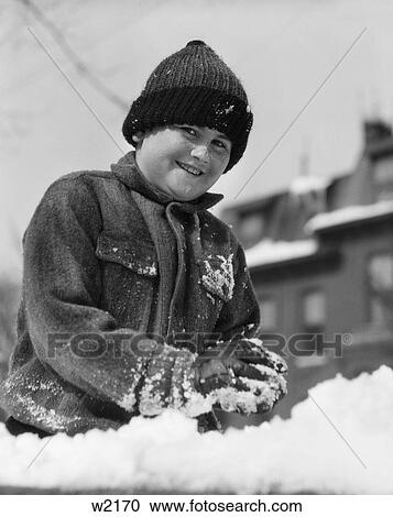Stock Image - 1930 1930S Boy Playing In Snow Making Snowball . Fotosearch