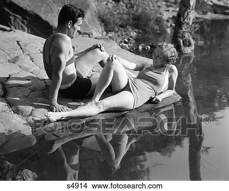 1930 1930S Couple Lying On Rocks Near Water Wearing Bathing Suits View Large Photo Image Picture - 1930 1930S Couple Lying On Rocks Near Water Wearing Bathing Suits . Fotosearch