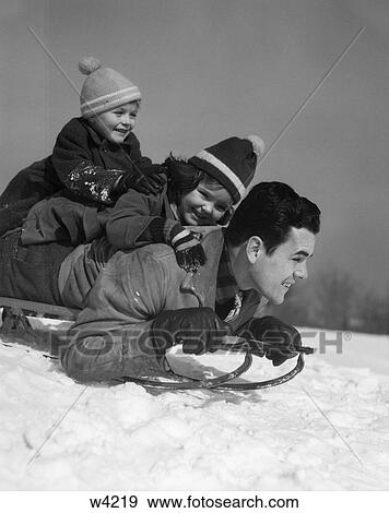 Stock Photo - 1930 1930S Father And Children Piled On Sled Going Down Hill In Snow Laughing . Fotosearch