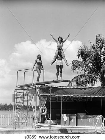 1930 1930S Girl On Boy'S Shoulders With Arms In Air Girl Standing On Diving Board Near Swimming Pool View Large Photo Image Stock Photo - 1930 1930S Girl On Boy'S Shoulders With Arms In Air Girl Standing On Diving Board Near Swimming Pool . Fotosearch