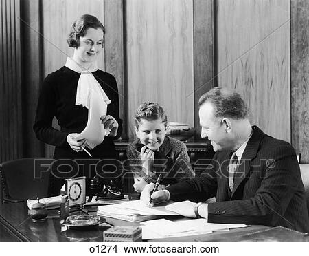 1930 1930S Little Boy Leaning On Mans Desk Woman Secretary Standing Office View Large Photo Image Picture - 1930 1930S Little Boy Leaning On Mans Desk Woman Secretary Standing Office. Fotosearch