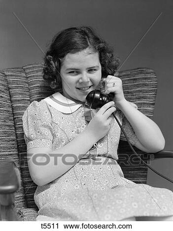Stock Image - 1930 1930S Little Girl Sitting In Chair Talking On Telephone . Fotosearch