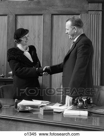1930 1930S Man Shaking Hands With Woman At Desk In Office View Large Photo Image Stock Photography - 1930 1930S Man Shaking Hands With Woman At Desk In Office . Fotosearch