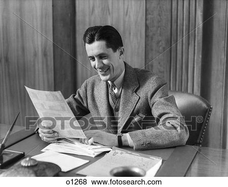 1930 1930S Man Sitting At Desk In Office Reading Through Papers View Large Photo Image Stock Photo - 1930 1930S Man Sitting At Desk In Office Reading Through Papers. Fotosearch