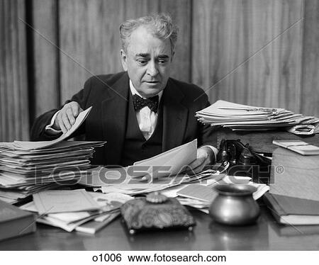 1930 1930S Man Sitting At Desk Looking Through Papers Busy Office Worker View Large Photo Image Stock Photograph - 1930 1930S Man Sitting At Desk Looking Through Papers Busy Office Worker . Fotosearch