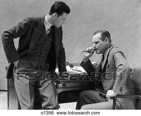 1930 1930S Two Men At Desk Talking One Man Smoking Cigar View Large Photo Image Stock Photograph - 1930 1930S Two Men At Desk Talking One Man Smoking Cigar . Fotosearch