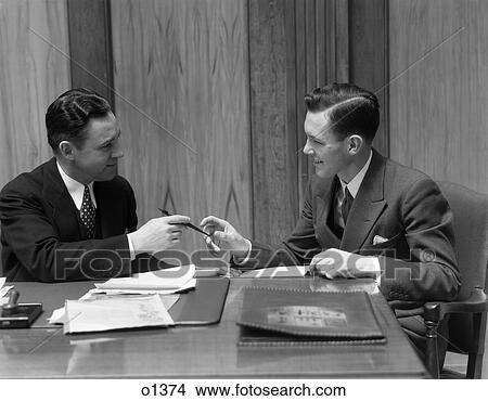 1930 1930S Two Men In Office Exchanging Pen View Large Photo Image Picture - 1930 1930S Two Men In Office Exchanging Pen . Fotosearch